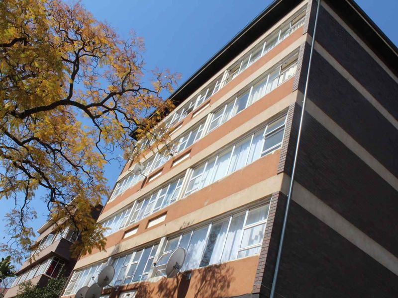 Low-angle view of a multi-story apartment building facade featuring brick construction and large windows.