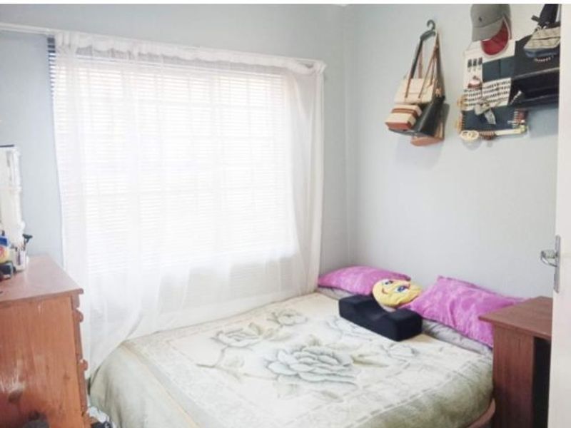 A compact bedroom featuring a window with blinds and curtains, providing natural light to the space.