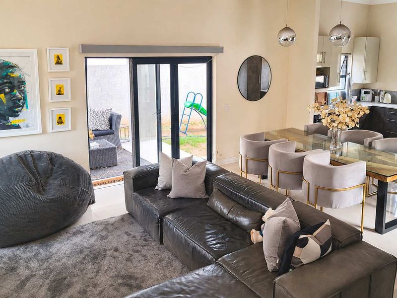 Spacious open-plan living and dining area featuring a modern kitchen with built-in appliances, sleek cabinetry, and direct access to the outdoor patio.