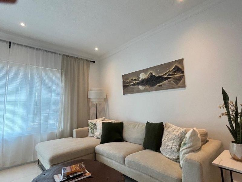 A well-maintained living room featuring recessed downlighting and decorative coving, creating a bright and comfortable atmosphere.