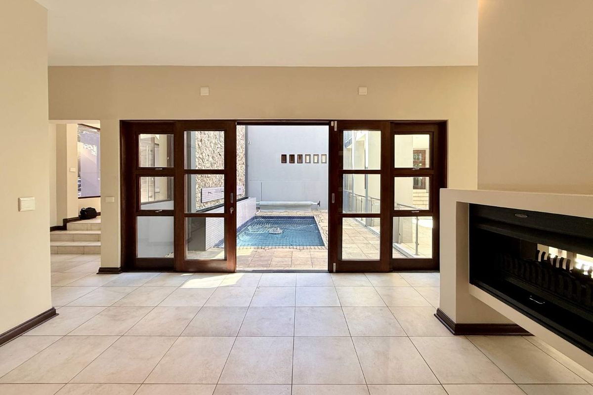 Spacious living area featuring large wooden sliding doors opening onto a private courtyard with a small plunge pool and built-in fireplace.