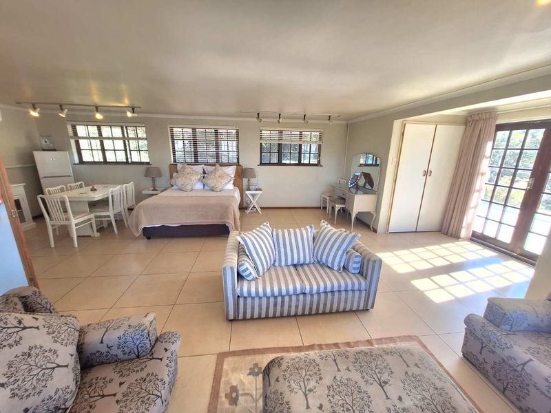 Spacious open-plan living and bedroom area featuring tiled floors, built-in storage, and direct access to the outdoors through glass-paned french doors.