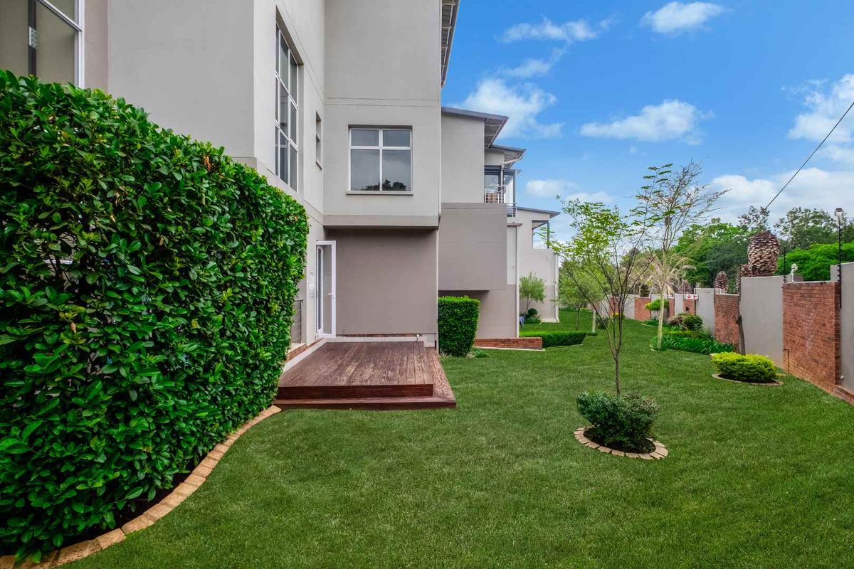 A well-maintained rear garden featuring a timber deck, manicured lawn, and established hedging, providing a private outdoor space.