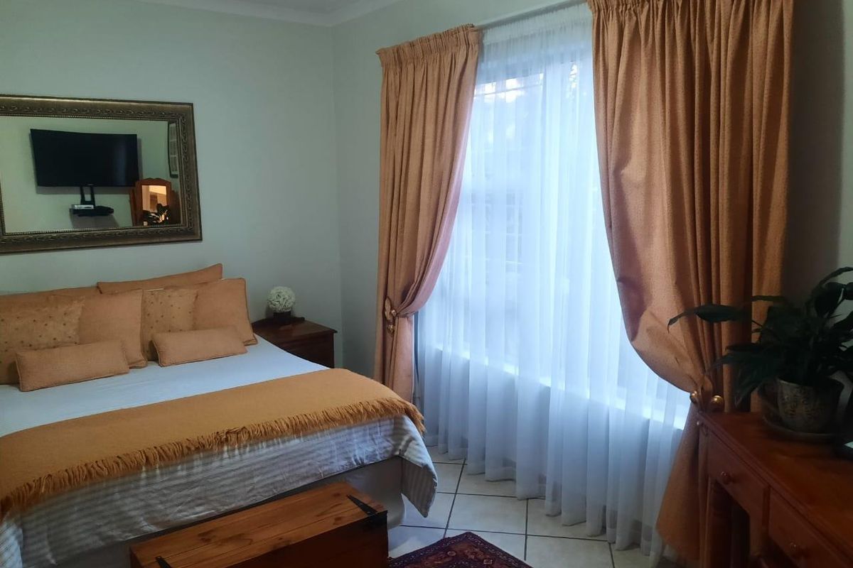 A bedroom featuring tiled flooring and window treatments, offering a functional space with neutral wall finishes.