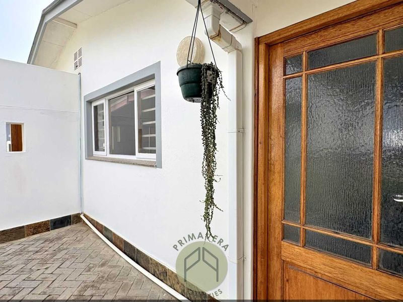 A well-maintained front entrance featuring a solid timber door with textured glass panels and paved exterior flooring.