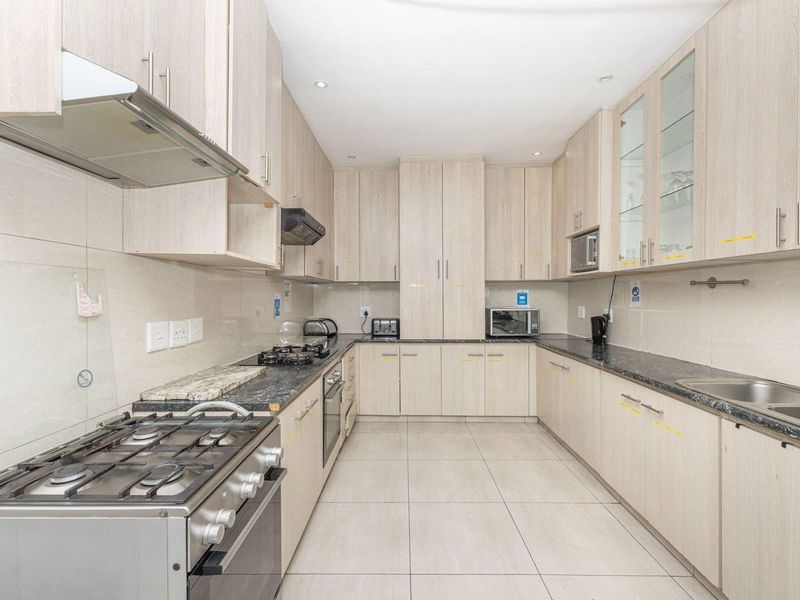 A well-maintained kitchen featuring light wood-finish cabinetry, granite countertops, a gas stove, and ample storage space with integrated appliances.