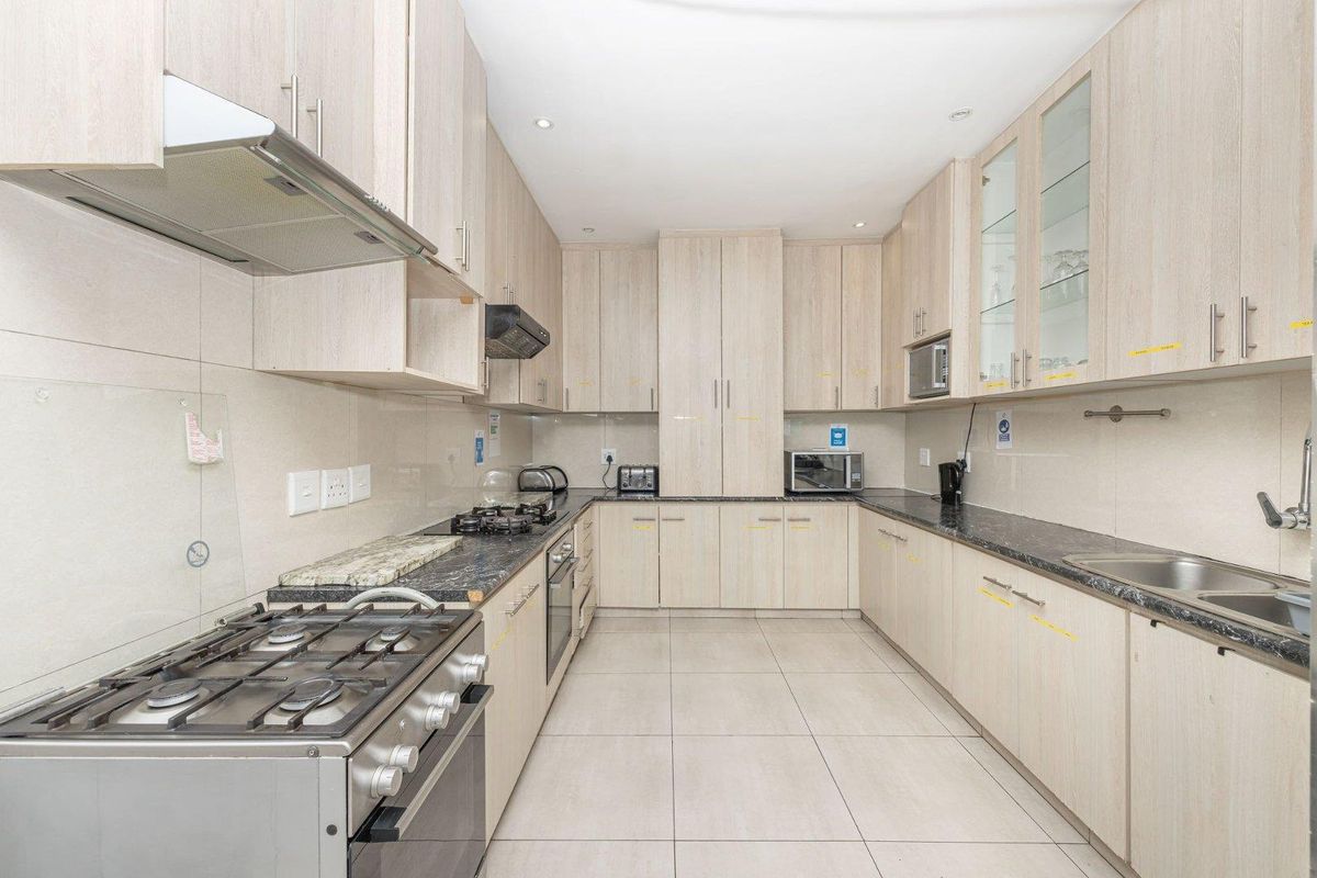 A well-maintained kitchen featuring light wood-finish cabinetry, granite countertops, a gas stove, and ample storage space with integrated appliances.