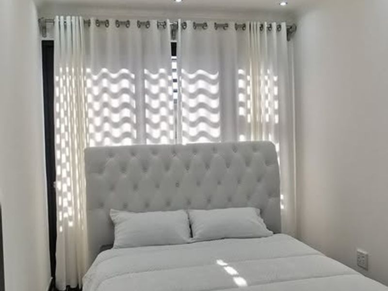 A modern bedroom featuring polished tiled flooring, recessed downlighting, and a decorative crystal ceiling fixture, creating a bright and contemporary sleeping space.