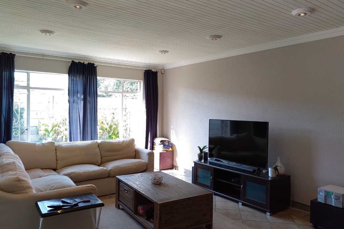A comfortable living room featuring tiled flooring, a textured tongue and groove ceiling, and recessed downlighting, providing a bright and functional space.