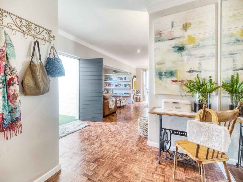 Welcoming entrance hall featuring classic parquet flooring and built-in shelving, leading into an open-plan living area.