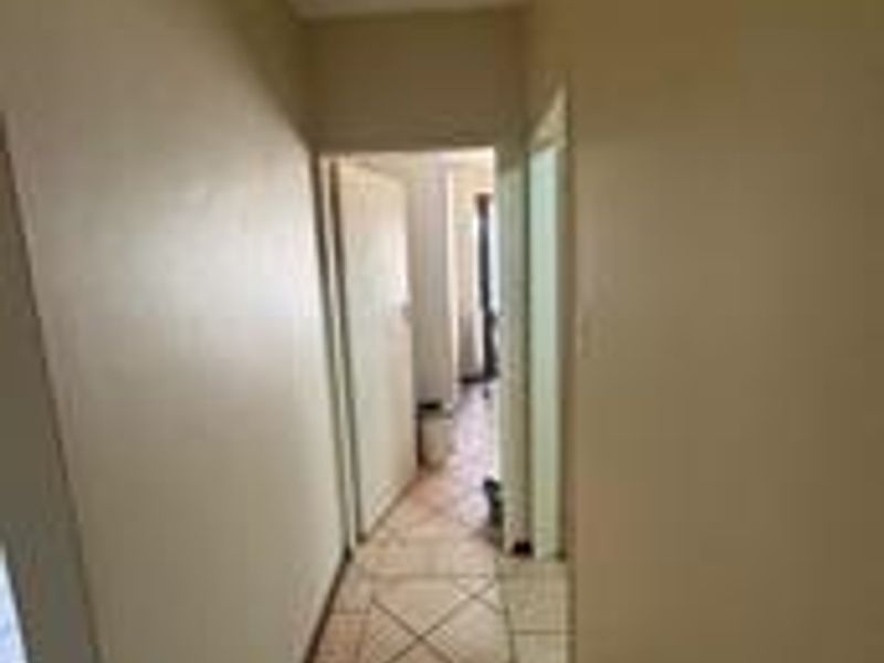 A narrow interior hallway featuring tiled flooring, connecting multiple rooms within the apartment.