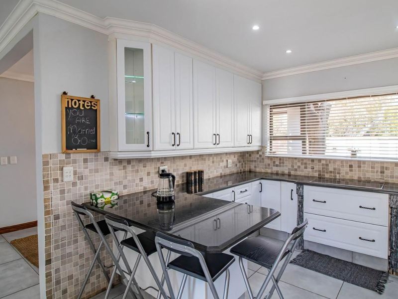 A well-maintained kitchen featuring white cabinetry, dark granite countertops, a tiled backsplash, and recessed lighting, offering a functional and clean workspace.
