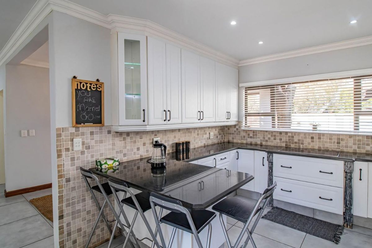 A well-maintained kitchen featuring white cabinetry, dark granite countertops, a tiled backsplash, and recessed lighting, offering a functional and clean workspace.