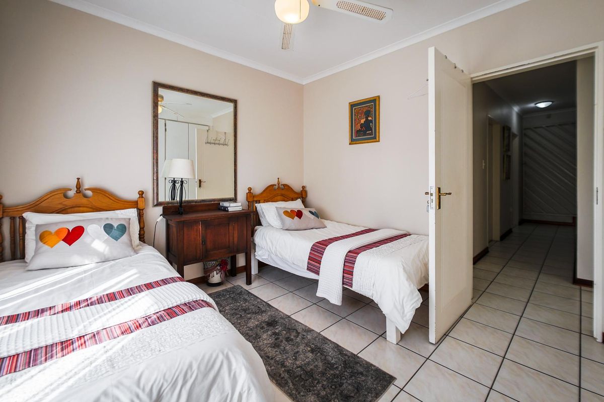 A functional bedroom featuring tiled flooring and a ceiling fan, providing a comfortable space with direct access to the hallway.