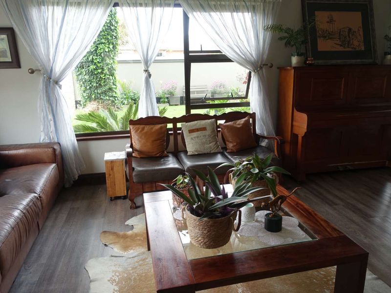 A comfortable living room featuring modern laminate flooring and a large window providing natural light and views of the garden.