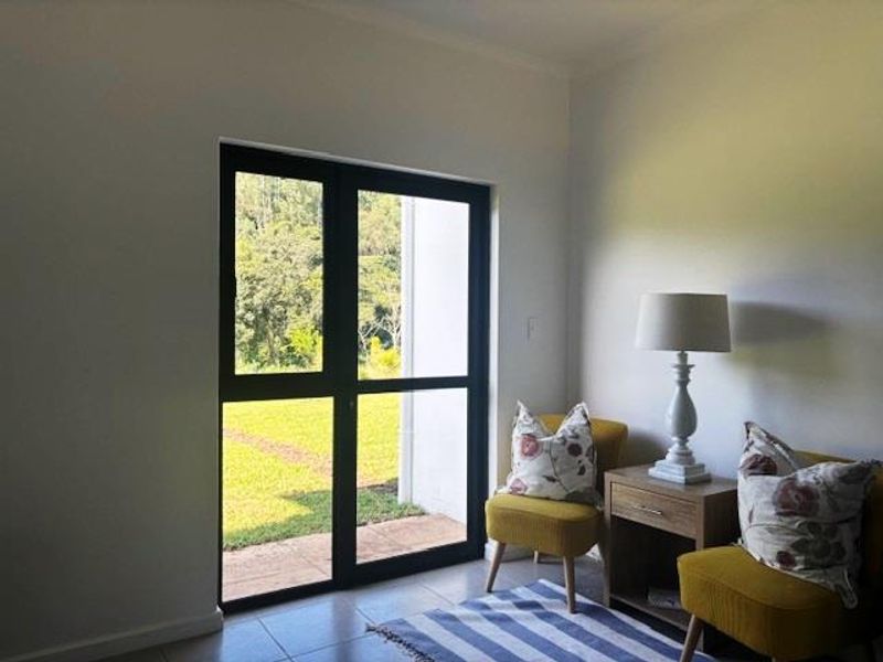 A bright living area featuring large black-framed glass doors that provide direct access to the outdoor garden space.