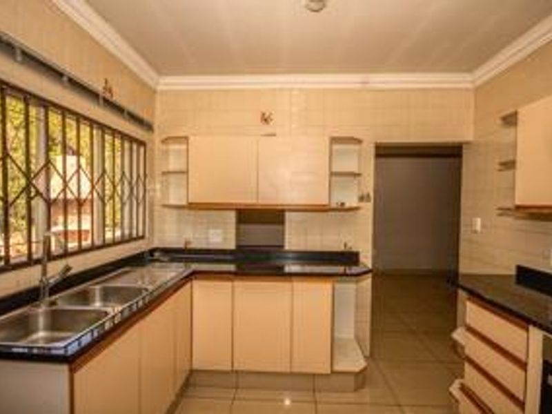 A functional kitchen featuring built-in cabinetry, granite countertops, a double basin sink, and an integrated oven, offering a clean and practical workspace.