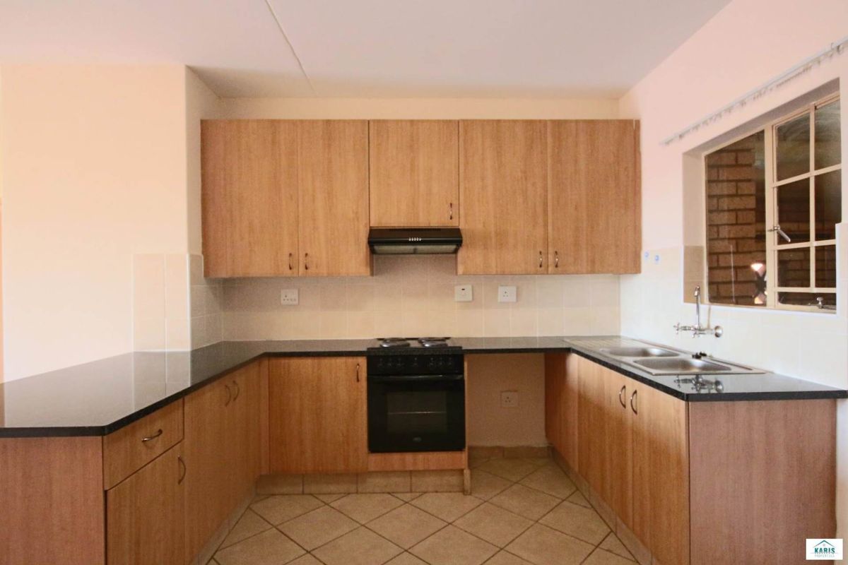 A functional kitchen featuring laminate cabinetry, granite countertops, a built-in oven with hob, and a double sink with tiled backsplash.