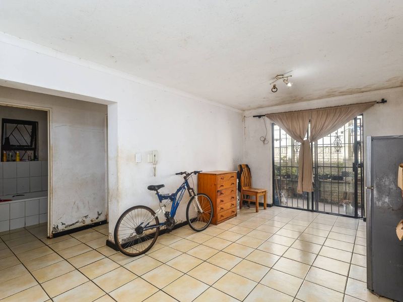 Open plan living area featuring tiled flooring and a sliding door leading to an outdoor space, requiring cosmetic refurbishment and wall repairs.