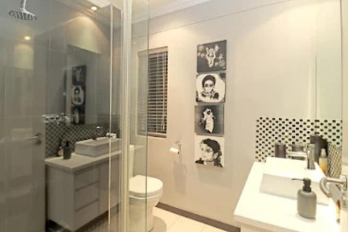 Modern bathroom featuring a glass-enclosed shower with a rain shower head, dual vanity areas with vessel sinks, and contemporary tiled splashbacks.