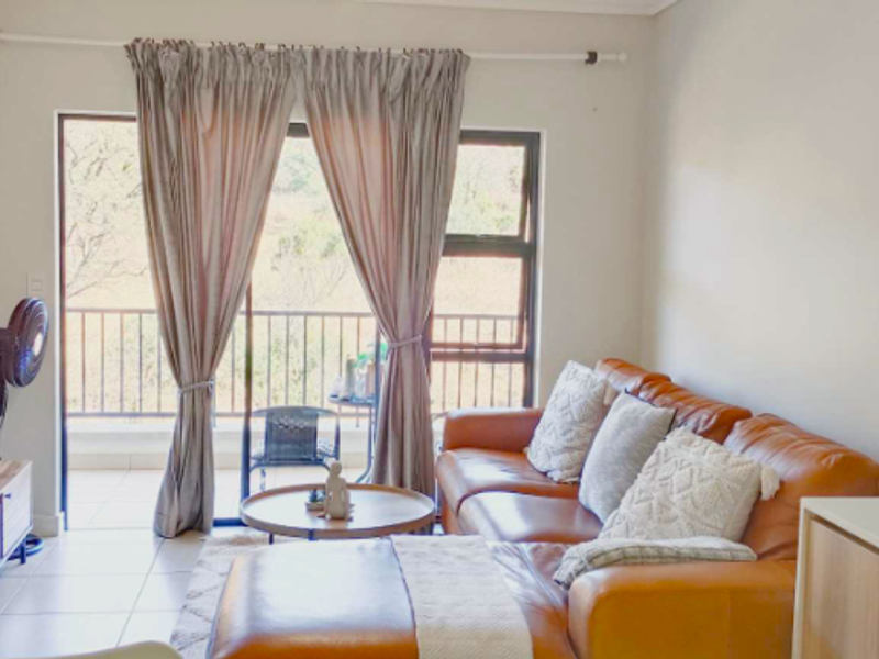Open-plan living area featuring tiled floors, neutral walls, and direct access to a private balcony through large sliding glass doors.