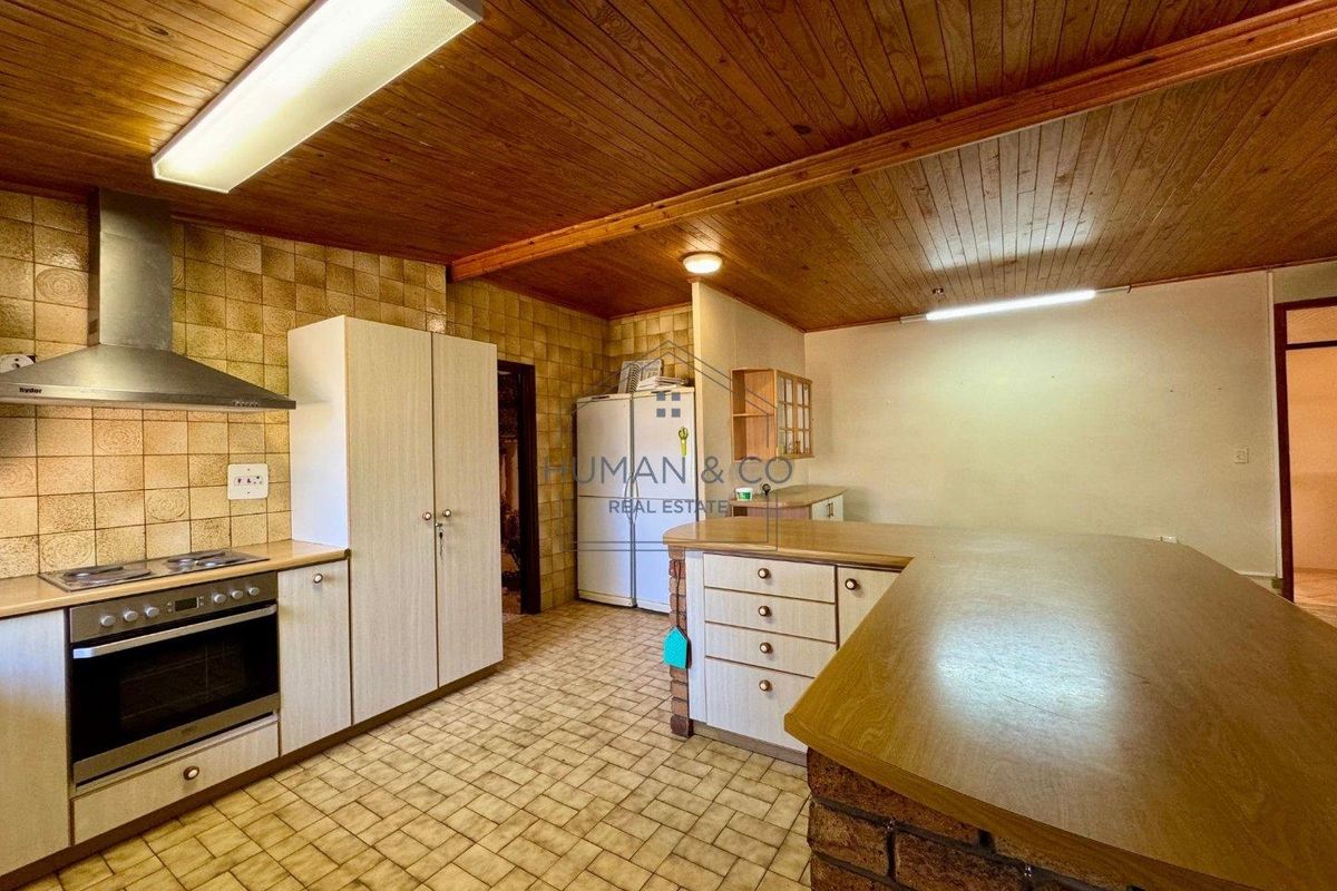 A dated kitchen featuring wood panel ceilings, tiled flooring, built-in cabinetry, and a breakfast bar counter.
