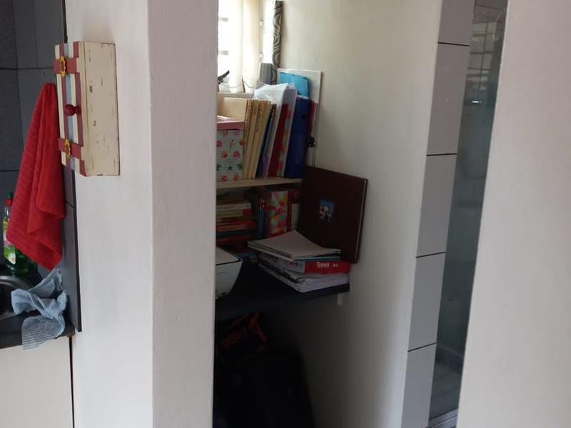 A compact utility or storage nook featuring built-in shelving and tiled flooring, situated between the kitchen and bathroom areas.