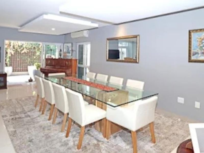 Spacious dining area featuring tiled flooring, a recessed ceiling detail, and sliding glass doors providing access to the outdoor patio area.