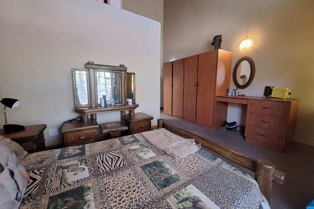 Spacious bedroom featuring high vaulted ceilings, built-in wooden wardrobe cabinetry, and a matching built-in vanity unit.