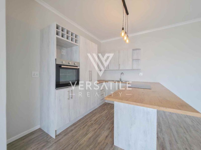 Modern kitchen featuring light wood-grain cabinetry, a built-in oven, wine storage, and a functional island with a laminate countertop.
