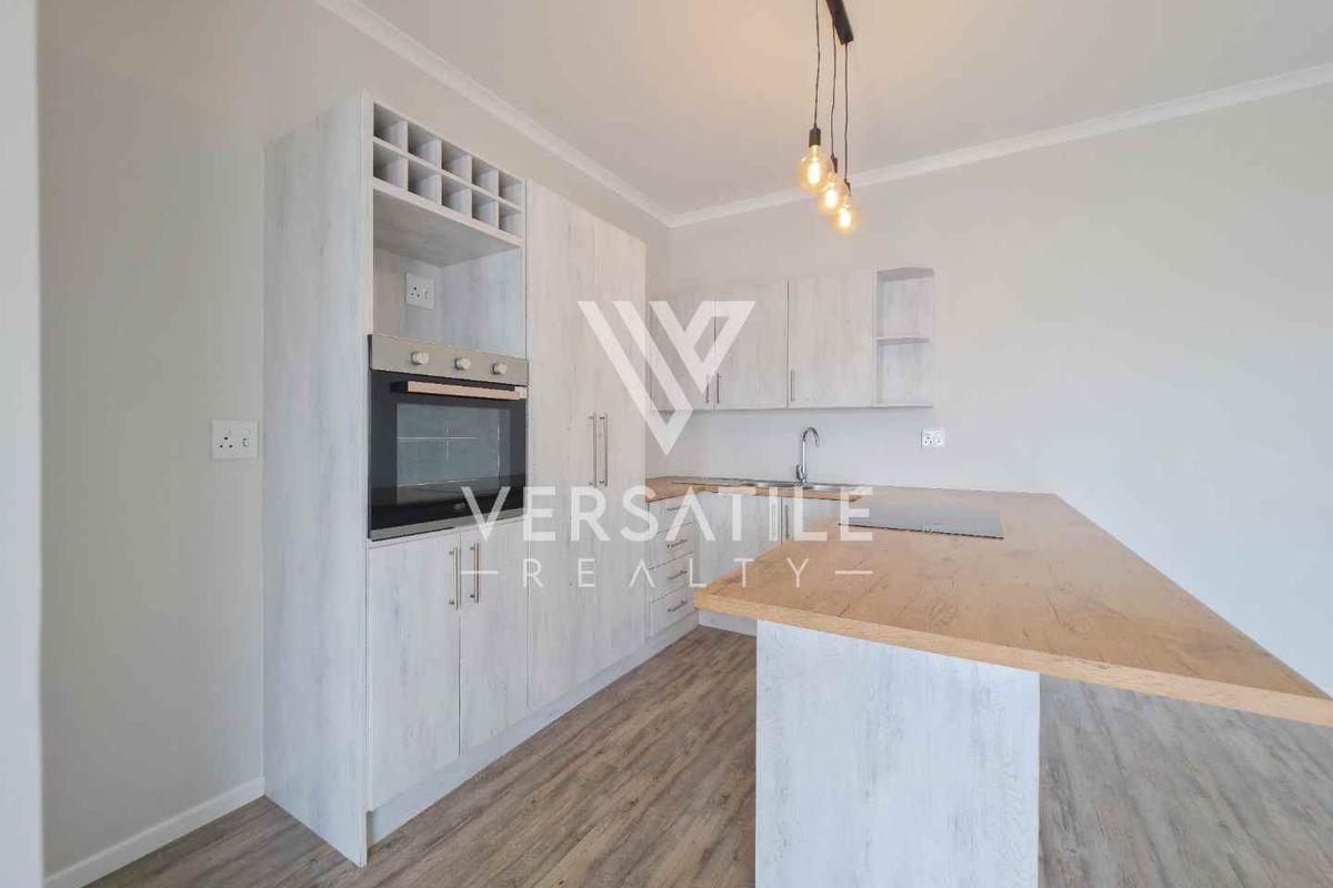 Modern kitchen featuring light wood-grain cabinetry, a built-in oven, wine storage, and a functional island with a laminate countertop.