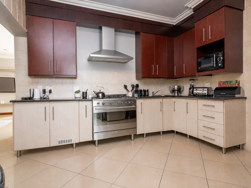 A well-maintained kitchen featuring two-tone cabinetry, granite countertops, a stainless steel gas stove with extractor fan, and a built-in microwave.