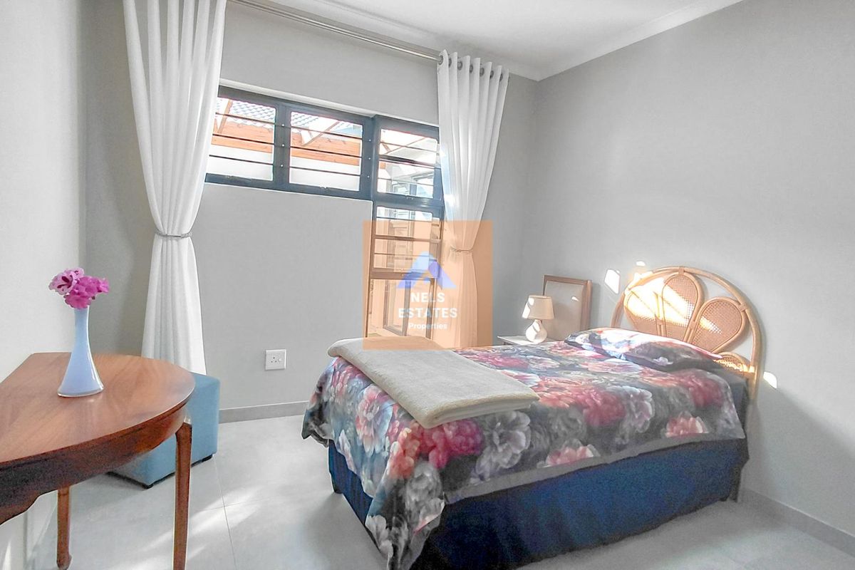A well-lit bedroom featuring neutral wall tones, tiled flooring, and aluminium window frames with security bars.