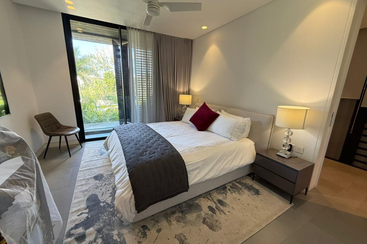 A modern bedroom featuring large sliding glass doors leading to a balcony, recessed lighting, and a ceiling fan.