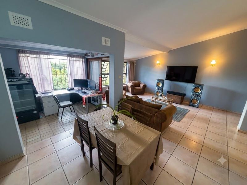 Spacious open-plan living and dining area featuring tiled flooring, neutral wall tones, and ample natural light, creating a versatile multi-functional living space.