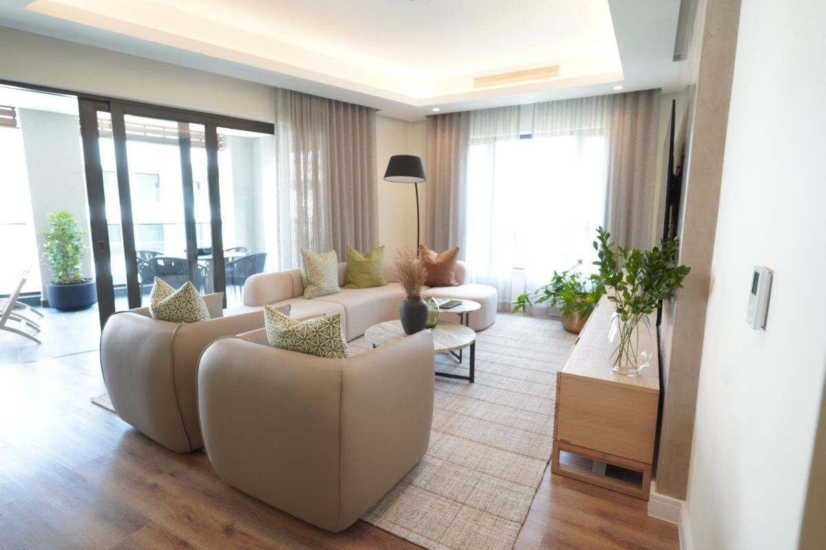 Modern living room featuring recessed ceiling lighting, laminate flooring, and large sliding glass doors providing seamless access to the outdoor balcony area.