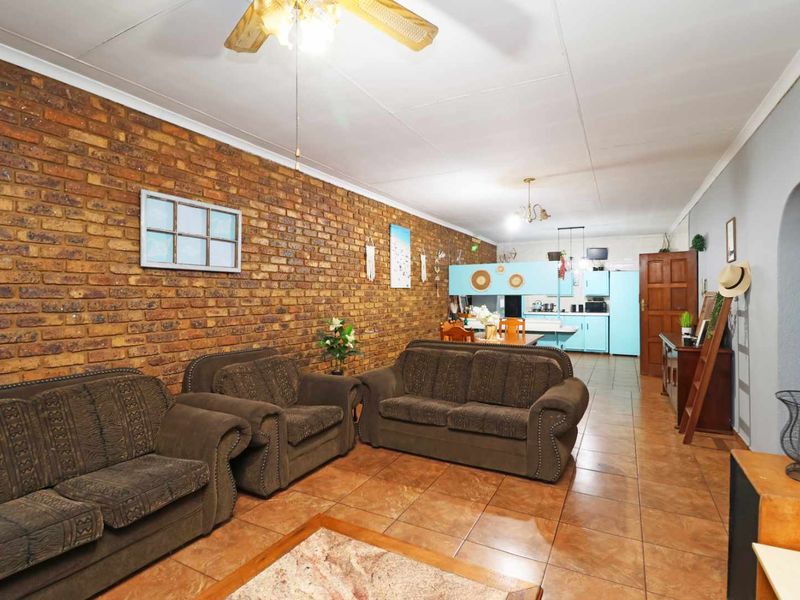Open-plan living and kitchen area featuring exposed brick walls, tiled flooring, and a ceiling fan, providing a functional and connected living space.