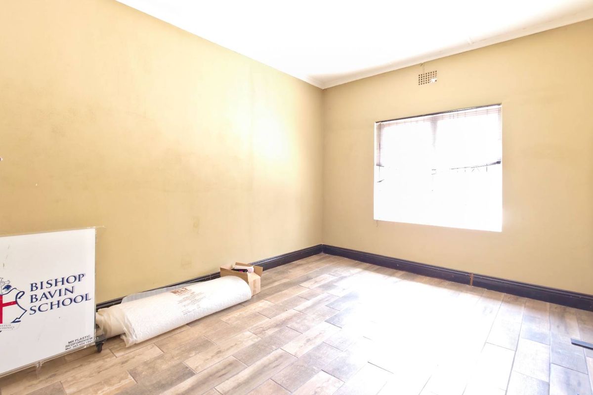 A vacant room featuring neutral wall tones, tiled flooring, and a window providing natural light, suitable for use as a bedroom or office space.