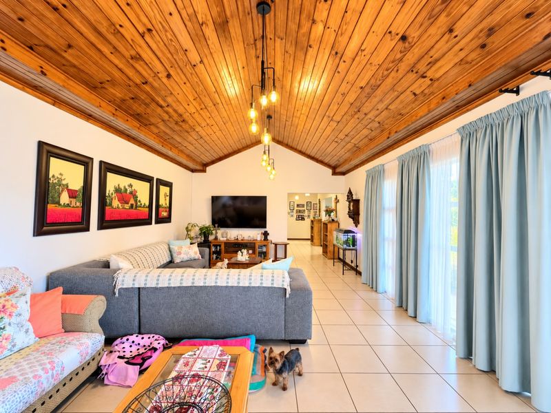 Spacious living room featuring a high vaulted timber ceiling, tiled flooring, and large sliding glass doors that provide ample natural light.