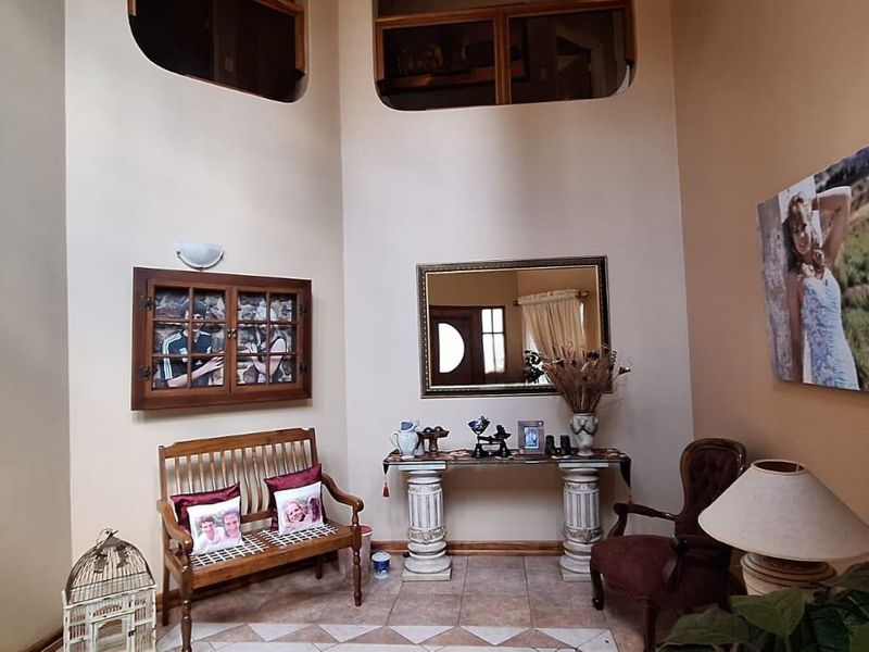 Spacious double-volume entrance hall featuring tiled flooring, arched architectural details, and a secure metal gate.