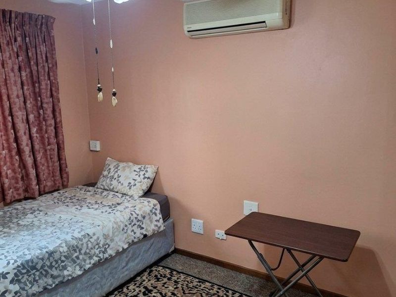 A bedroom featuring a ceiling fan, wall-mounted air conditioning unit, and standard electrical fixtures.
