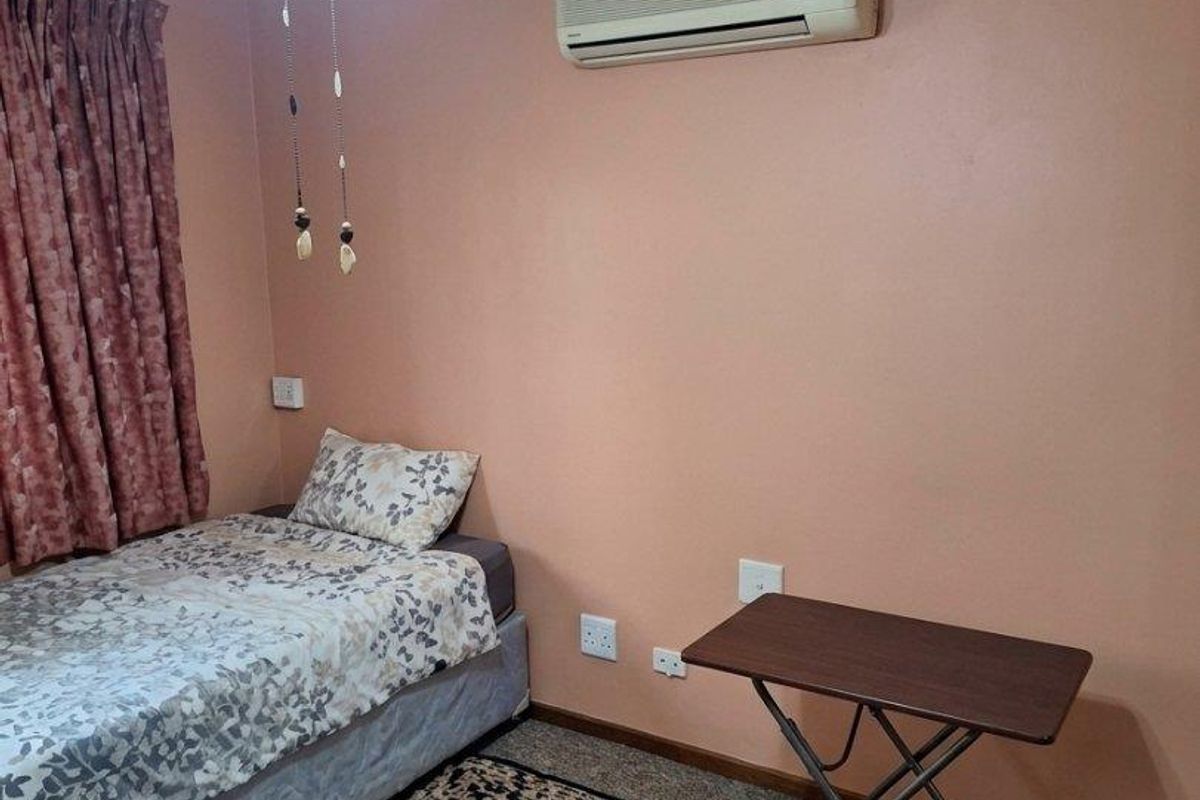A bedroom featuring a ceiling fan, wall-mounted air conditioning unit, and standard electrical fixtures.
