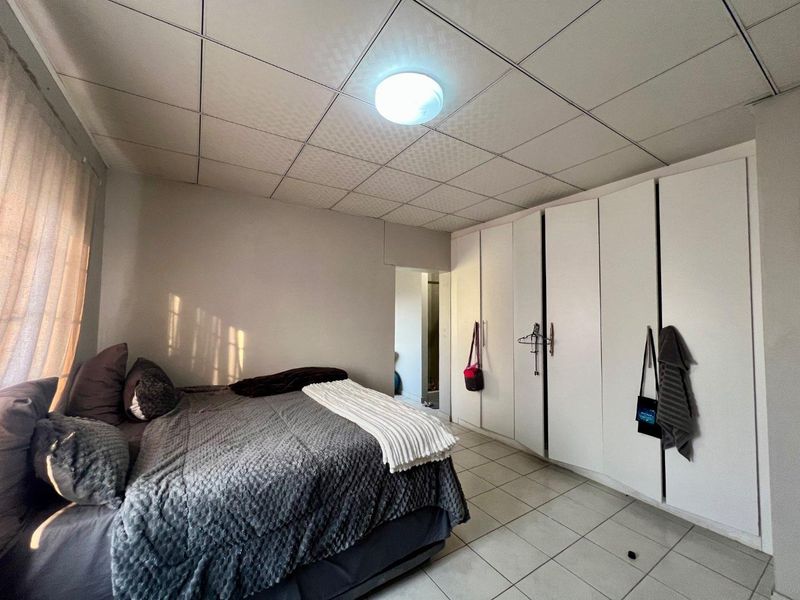A bedroom featuring tiled flooring, a drop ceiling, and extensive built-in cupboard storage.