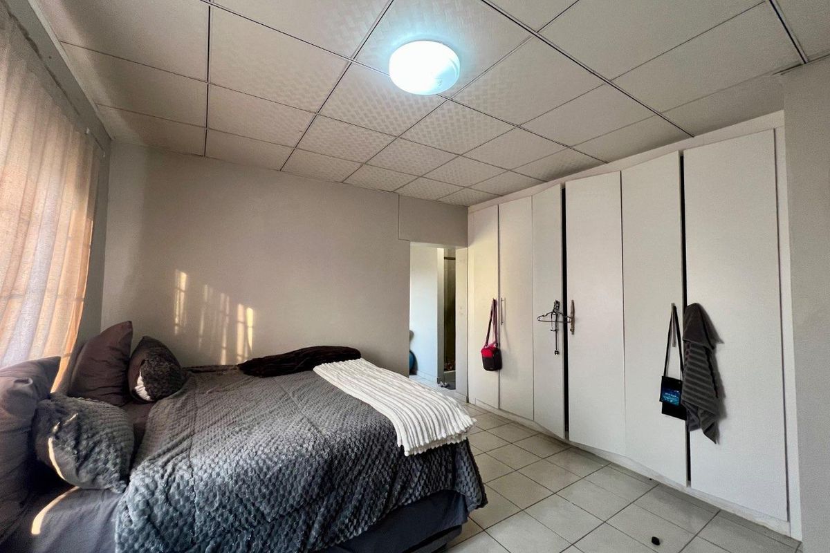 A bedroom featuring tiled flooring, a drop ceiling, and extensive built-in cupboard storage.