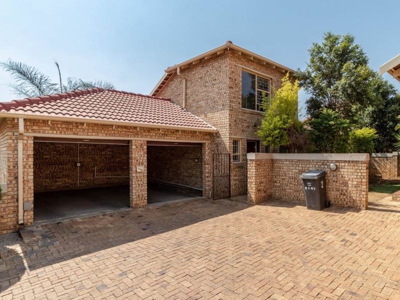 Front exterior view of a double-storey townhouse featuring a double garage, facebrick facade, and paved driveway.