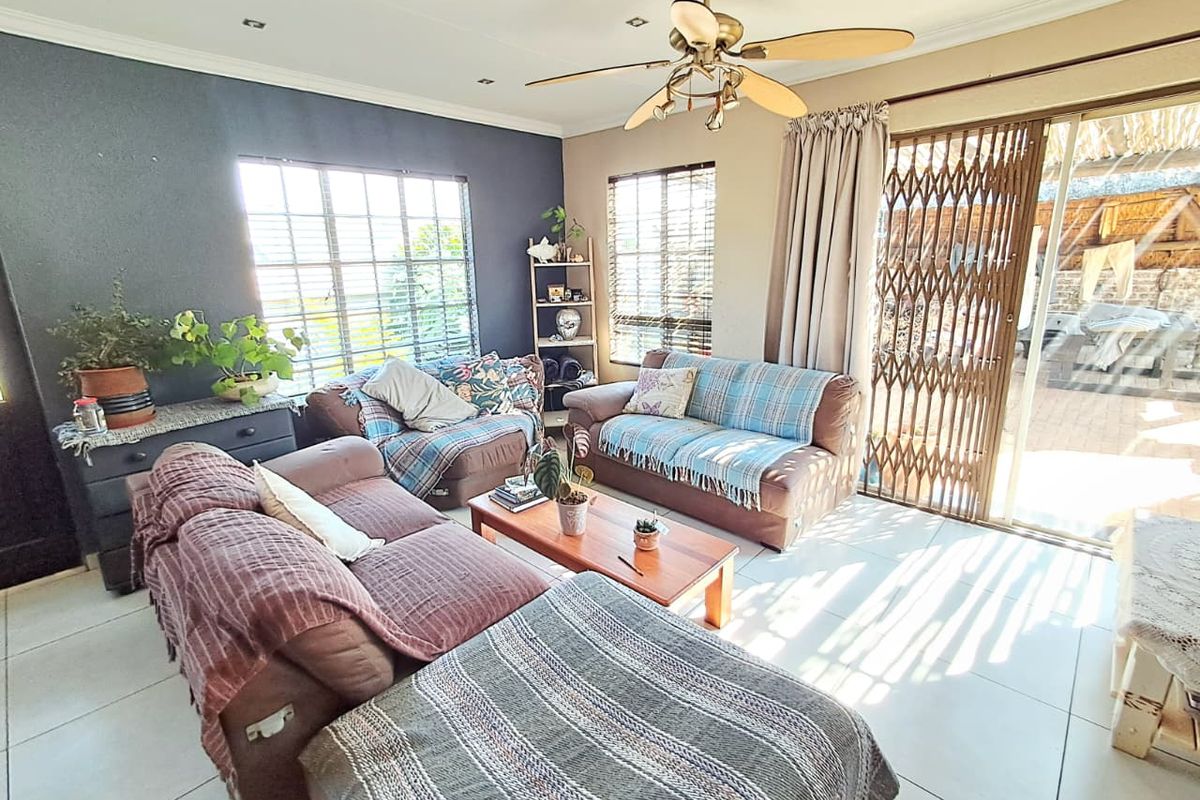 A bright living room featuring tiled flooring, a ceiling fan, and sliding glass doors that provide direct access to the outdoor patio area.
