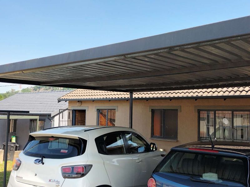 Front exterior view of the property featuring a metal carport structure and tiled roof.