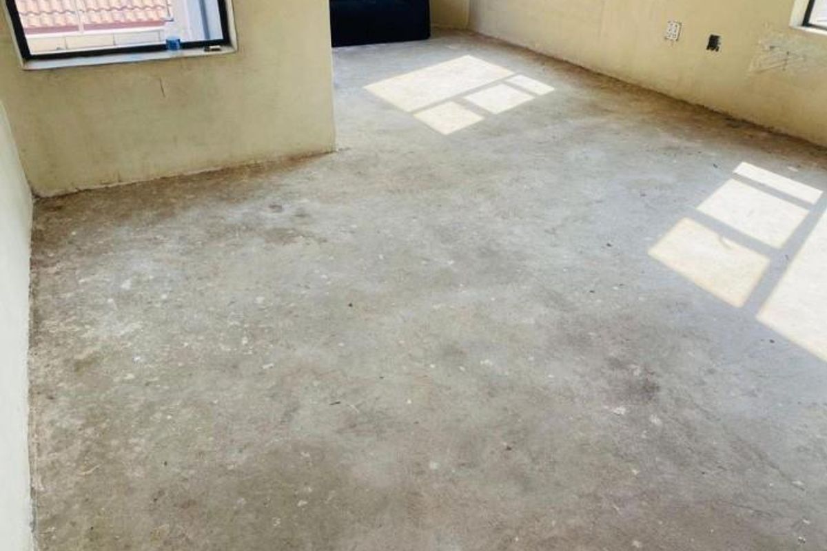 An unfinished bedroom space featuring exposed concrete flooring and unpainted walls, awaiting final flooring and decorative finishes.