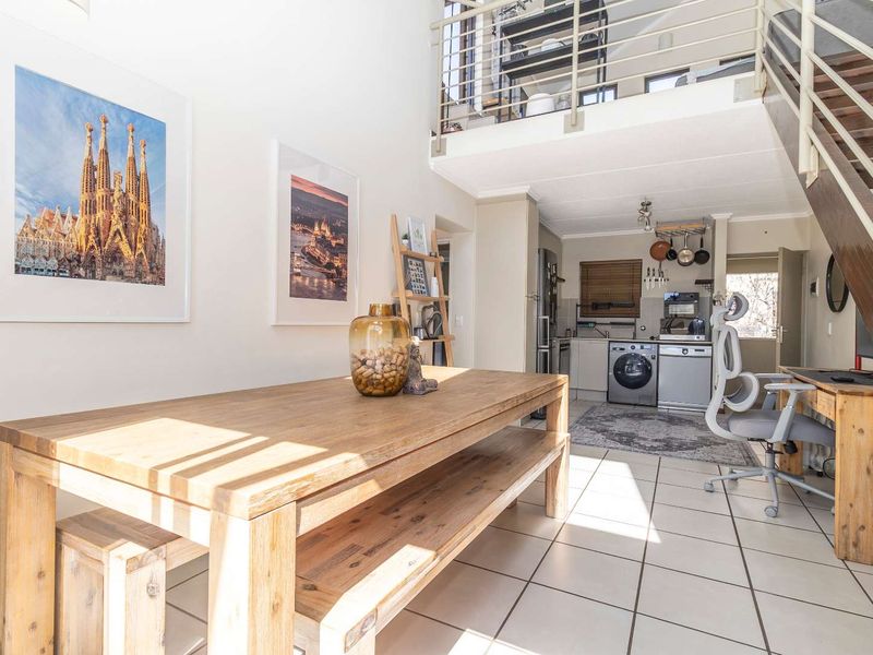 Open-plan living area featuring a mezzanine level, tiled flooring, and a functional kitchen space with built-in cabinetry.