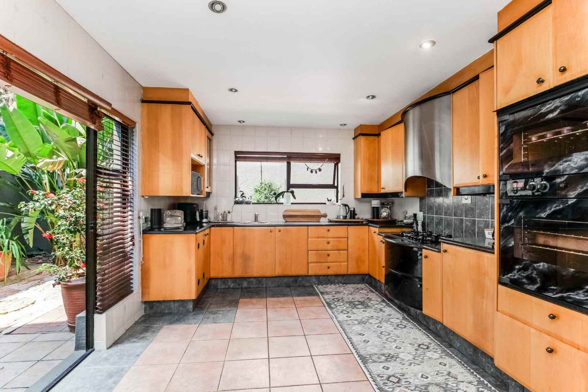 A functional kitchen featuring wooden cabinetry, built-in oven, gas hob, and direct access to an outdoor patio area through a sliding glass door.